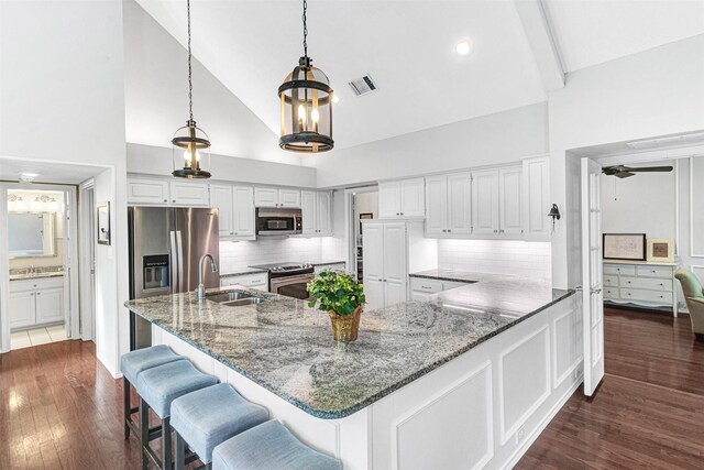 2203 Glascow Ct, Carrollton, TX 75007 - kitchen featuring stainless steel appliances, a sink, high vaulted ceiling, dark wood-style flooring, and stone counters