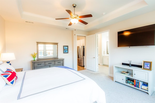 7721 Haddington, The Colony, TX 75056 - bedroom featuring freestanding refrigerator, a raised ceiling, light colored carpet, and ensuite bath