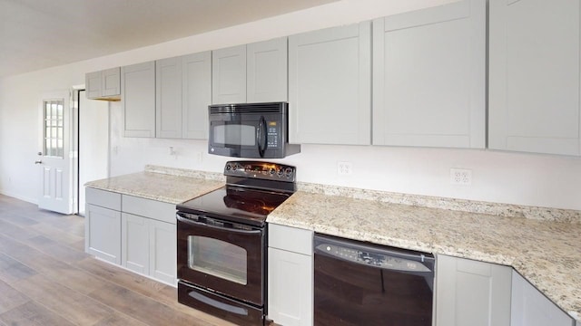 5604 5th St, Rochelle, TX 76872 - kitchen featuring black appliances, light wood-type flooring, light stone counters, and baseboards