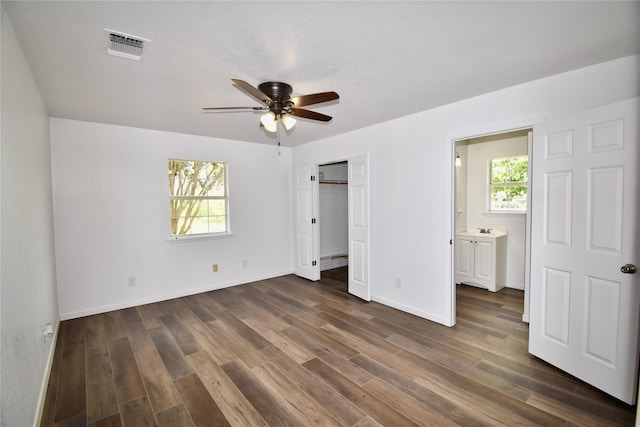 5604 5th St, Rochelle, TX 76872 - unfurnished bedroom featuring dark wood-style flooring, baseboards, ceiling fan, connected bathroom, and a closet