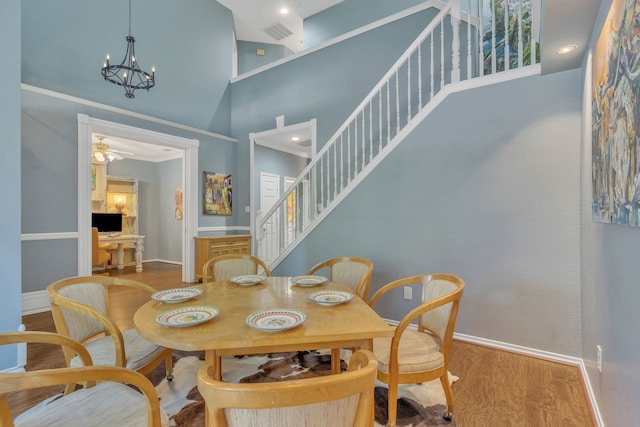 4001 Elmhill Dr, Plano, TX 75024 - dining area featuring a towering ceiling, wood finished floors, a chandelier, baseboards, and stairs