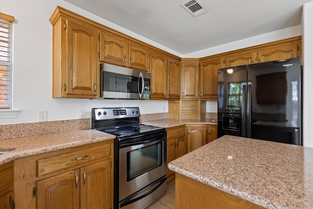 623 Madison Pl, Sherman, TX 75092 - kitchen with stainless steel appliances, brown cabinetry, light tile patterned flooring, and light stone counters