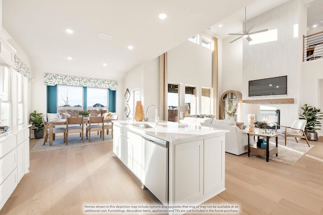 4622 Bel Air Dr, Midlothian, TX 76065 - kitchen with stainless steel dishwasher, a sink, open floor plan, light wood-style floors, and white cabinetry