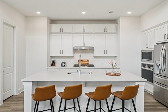 422 Firecrest Ln, Celina, TX 75009 - kitchen featuring appliances with stainless steel finishes, under cabinet range hood, wood finished floors, white cabinets, and recessed lighting