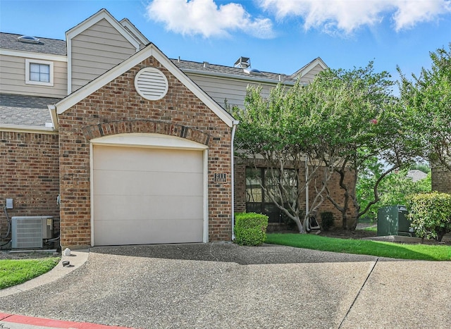 211 Cimarron Trl Unit 8, Irving, TX 75063 - view of front of property with central AC unit, driveway, brick siding, a garage, and a shingled roof