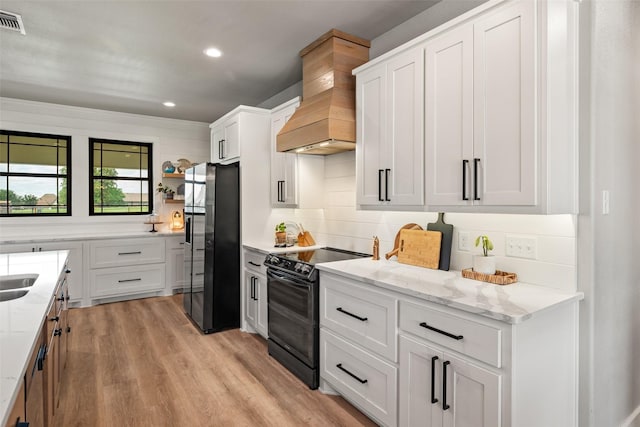100 Tall Grass Ct, Weatherford, TX 76087 - kitchen with black range with electric stovetop, custom range hood, freestanding refrigerator, light stone counters, and recessed lighting