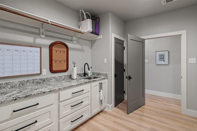 100 Tall Grass Ct, Weatherford, TX 76087 - kitchen with a sink, light wood-type flooring, white cabinets, light stone countertops, and baseboards
