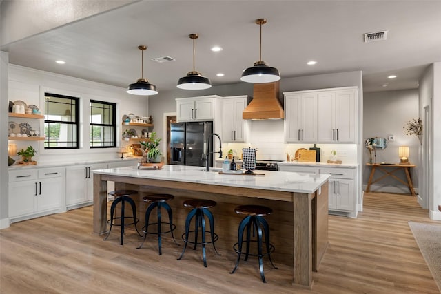 100 Tall Grass Ct, Weatherford, TX 76087 - kitchen with open shelves, black refrigerator with ice dispenser, a breakfast bar, custom range hood, and recessed lighting