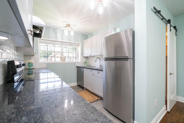 405 Houston St, Sulphur Springs, TX 75482 - kitchen with stainless steel appliances, a sink, decorative backsplash, a barn door, and dark stone countertops