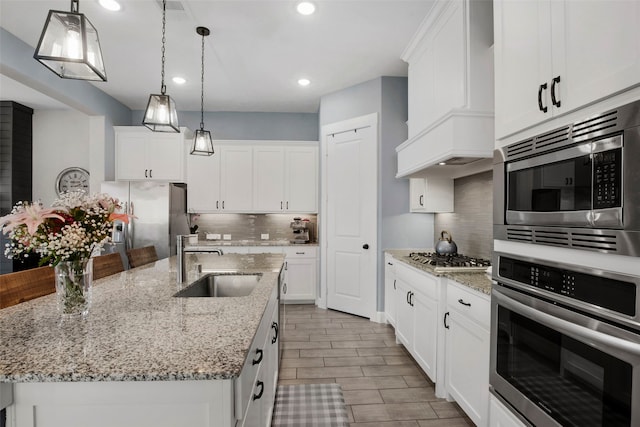 4860 Connor Pl, Fairview, TX 75069 - kitchen featuring stainless steel appliances, a sink, backsplash, a center island with sink, and white cabinetry