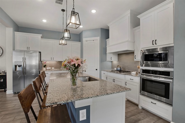4860 Connor Pl, Fairview, TX 75069 - kitchen featuring appliances with stainless steel finishes, wood finished floors, white cabinetry, a breakfast bar, and recessed lighting