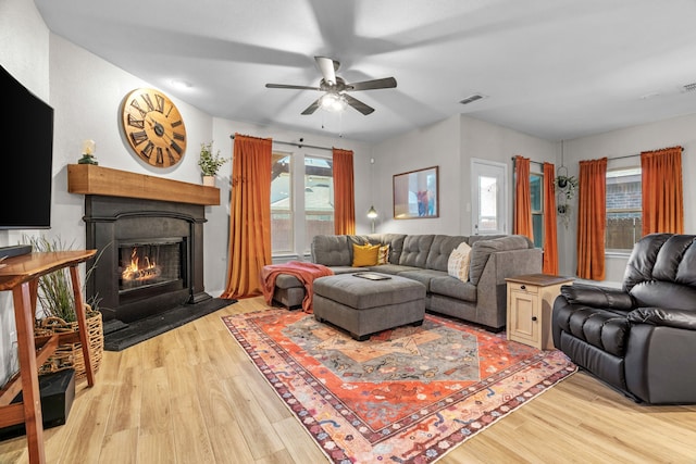15712 Oak Pointe Dr, Fort Worth, TX 76177 - living area with light wood-style floors, a ceiling fan, and a warm lit fireplace