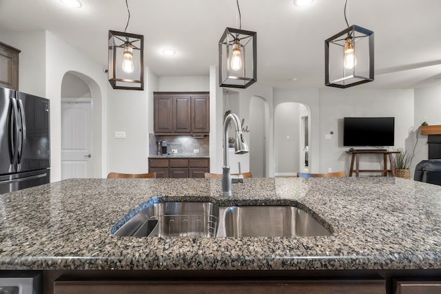 15712 Oak Pointe Dr, Fort Worth, TX 76177 - kitchen with freestanding refrigerator, a sink, arched walkways, dark stone countertops, and recessed lighting