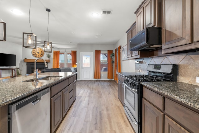 15712 Oak Pointe Dr, Fort Worth, TX 76177 - kitchen with appliances with stainless steel finishes, a sink, light wood-style floors, tasteful backsplash, and dark stone countertops