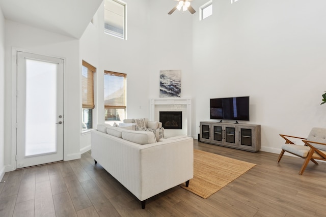 232 Lakewood Ln, Ponder, TX 76259 - living area featuring a glass covered fireplace, wood finished floors, a towering ceiling, and a ceiling fan