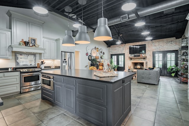 853 County Road 2215, Decatur, TX 76234 - kitchen with stainless steel appliances, brick wall, gray cabinetry, dark countertops, and a center island