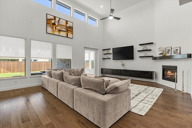 2012 Grover Ln, Rockwall, TX 75087 - living area with a ceiling fan, dark wood-style floors, a high ceiling, a glass covered fireplace, and baseboards