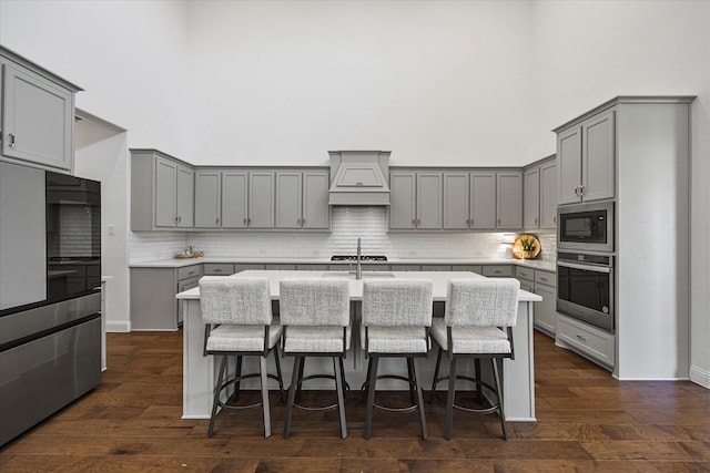 2012 Grover Ln, Rockwall, TX 75087 - kitchen with stainless steel appliances, gray cabinets, custom range hood, a high ceiling, and a breakfast bar area