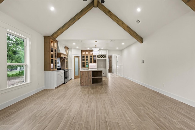 609 N Stewart St, Azle, TX 76020 - kitchen with stainless steel electric stove, beam ceiling, arched walkways, open floor plan, and light wood-style floors