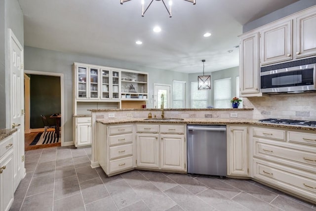 286 Lilac Ln, Southlake, TX 76092 - kitchen with appliances with stainless steel finishes, a sink, light stone countertops, glass insert cabinets, and decorative backsplash