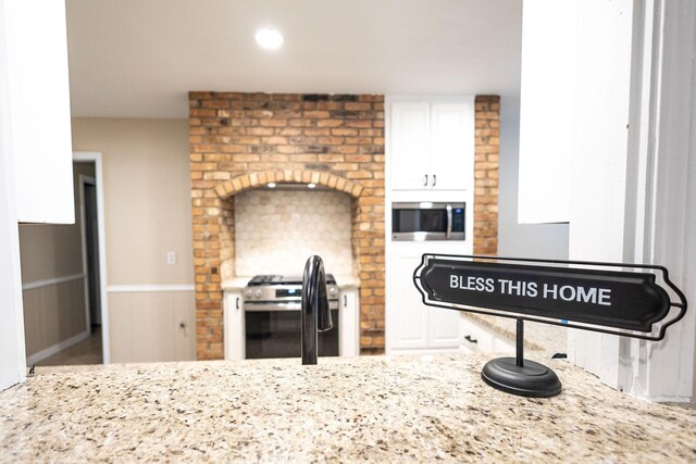 4701 Woodview St, Arlington, TX 76013 - kitchen featuring appliances with stainless steel finishes, white cabinetry, light stone counters, and a sink