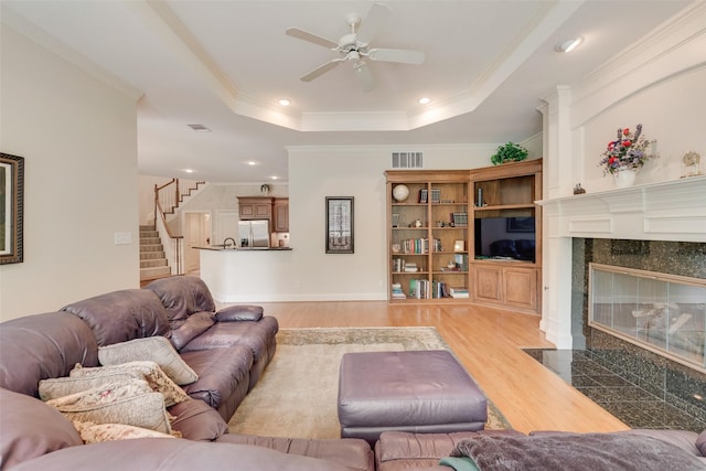 808 Country Club Dr, Heath, TX 75032 - living room featuring light wood-style flooring, a tray ceiling, a premium fireplace, a ceiling fan, and stairway