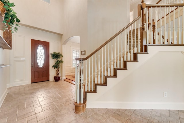 808 Country Club Dr, Heath, TX 75032 - foyer featuring arched walkways, baseboards, a high ceiling, stairs, and stone tile flooring