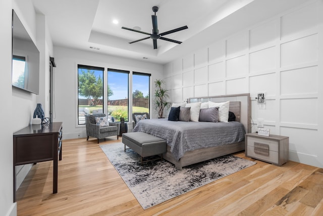 4940 Golden Bell Ln, Midlothian, TX 76065 - bedroom featuring a raised ceiling, a decorative wall, light wood-style floors, a ceiling fan, and recessed lighting