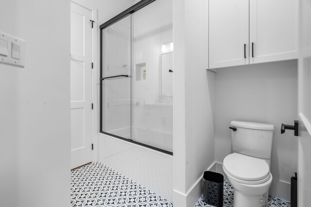 4940 Golden Bell Ln, Midlothian, TX 76065 - full bathroom featuring toilet, shower / bath combination with glass door, baseboards, and tile patterned flooring
