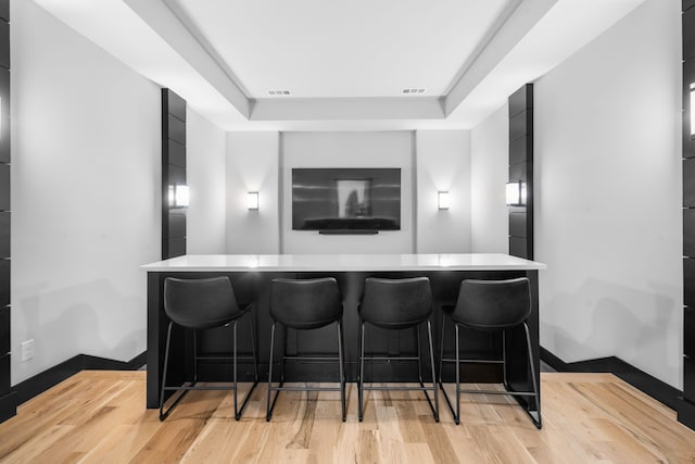 4940 Golden Bell Ln, Midlothian, TX 76065 - home theater room featuring light wood finished floors, a tray ceiling, and a bar