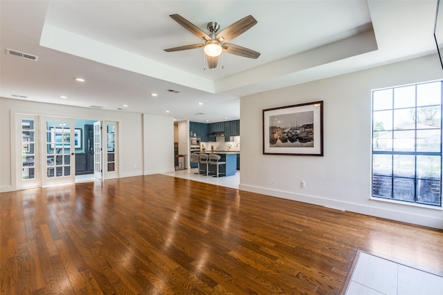 14815 Surveyor Blvd, Addison, TX 75001 - unfurnished living room featuring a ceiling fan, light wood finished floors, a raised ceiling, recessed lighting, and baseboards
