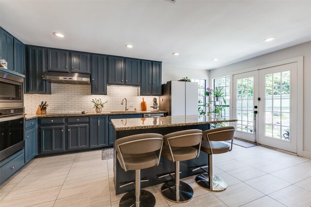 14815 Surveyor Blvd, Addison, TX 75001 - kitchen featuring appliances with stainless steel finishes, a sink, a kitchen bar, light stone counters, and recessed lighting