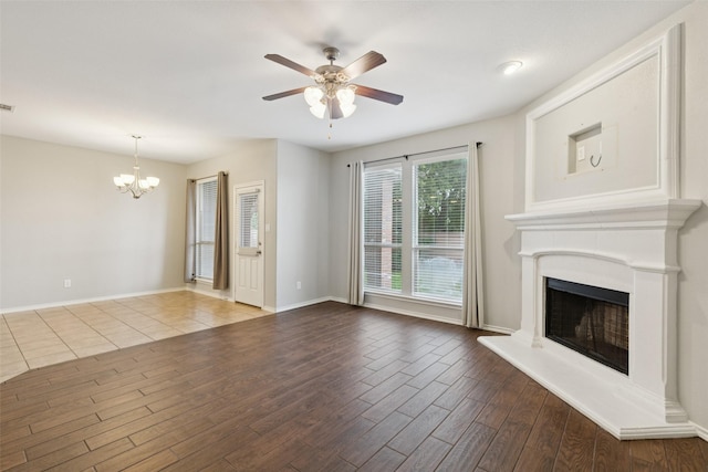 13100 Larks View Pt, Fort Worth, TX 76244 - unfurnished living room with a chandelier, wood finished floors, a fireplace with raised hearth, ceiling fan, and baseboards