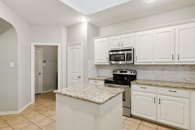13100 Larks View Pt, Fort Worth, TX 76244 - kitchen with appliances with stainless steel finishes, tasteful backsplash, light tile patterned floors, arched walkways, and white cabinets