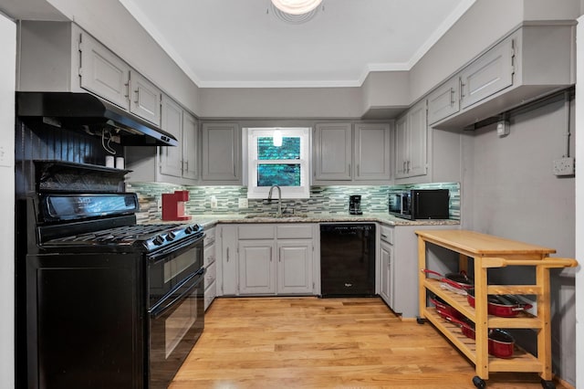 306 W Ross St, Waxahachie, TX 75165 - kitchen featuring black appliances, under cabinet range hood, a sink, light wood-style flooring, and decorative backsplash