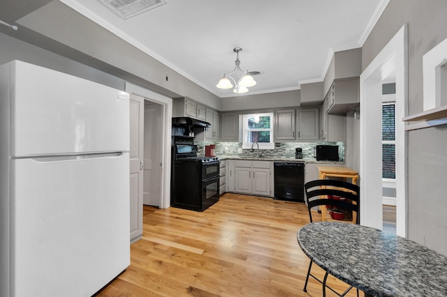 306 W Ross St, Waxahachie, TX 75165 - kitchen featuring black appliances, crown molding, a sink, a chandelier, and light wood finished floors