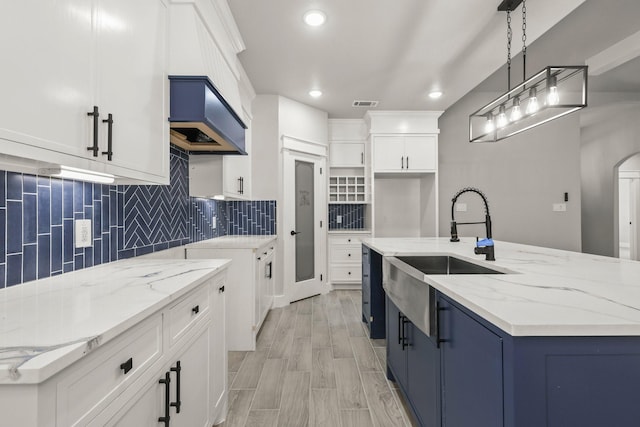 3813 Galvez Ave, Fort Worth, TX 76111 - kitchen with a sink, light stone counters, backsplash, decorative light fixtures, and a kitchen island with sink