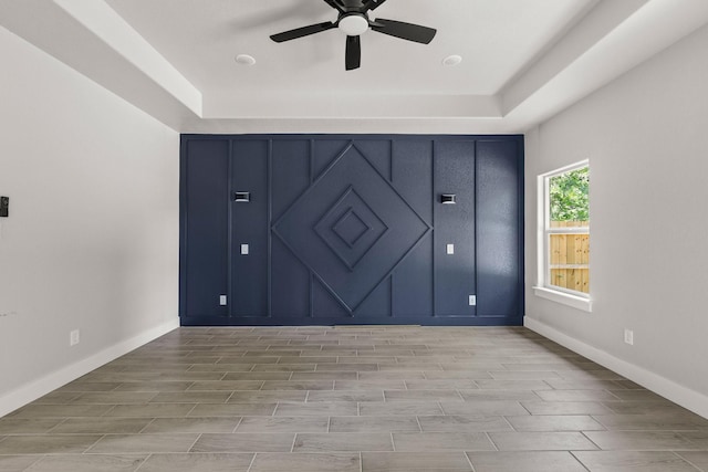 3813 Galvez Ave, Fort Worth, TX 76111 - unfurnished bedroom featuring wood finish floors, baseboards, ceiling fan, and a tray ceiling