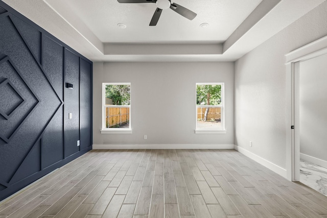3813 Galvez Ave, Fort Worth, TX 76111 - unfurnished bedroom with a tray ceiling, baseboards, light wood-type flooring, and ceiling fan