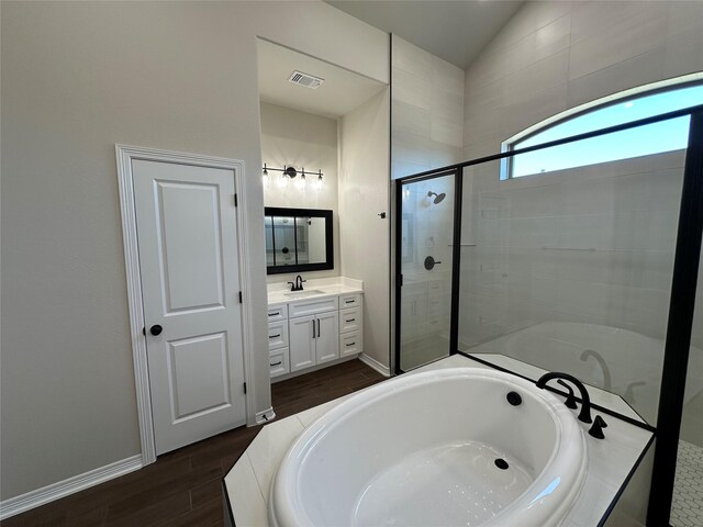 507 Magnolia Dr, Troy, TX 76579 - bathroom with a garden tub, vanity, a stall shower, wood finished floors, and vaulted ceiling