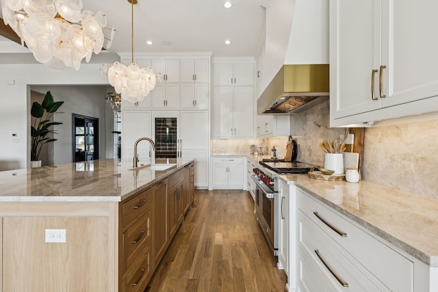 4309 American Pharoah Way, Celina, TX 75009 - kitchen featuring wall chimney range hood, a chandelier, double oven range, a sink, and wood finished floors