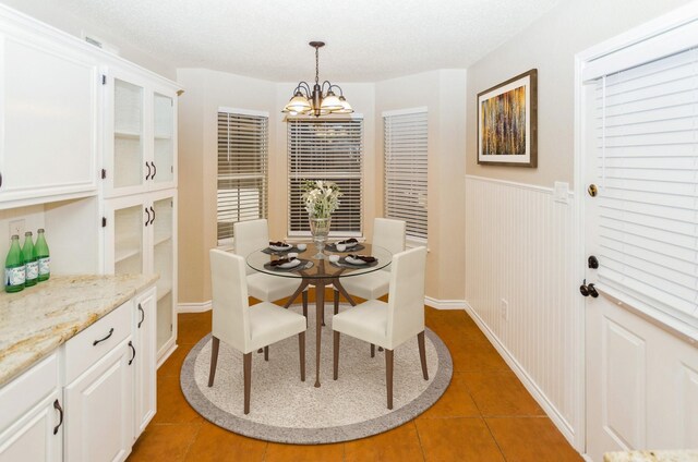 2229 Silverthorn Ln, Flower Mound, TX 75028 - dining area featuring a chandelier, light tile patterned floors, a wainscoted wall, and baseboards