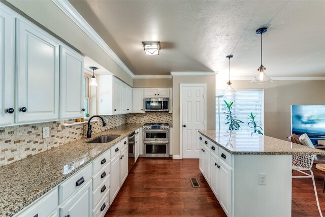 606 Kirby Ln, Richardson, TX 75080 - kitchen featuring stainless steel appliances, crown molding, dark wood-style flooring, and light stone counters
