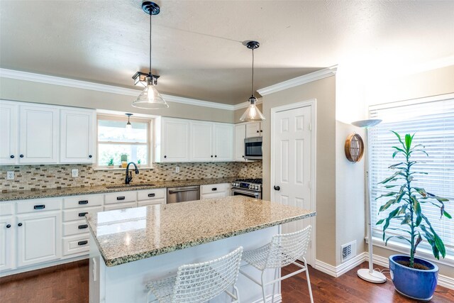 606 Kirby Ln, Richardson, TX 75080 - kitchen with stainless steel appliances, white cabinets, backsplash, dark wood-type flooring, and crown molding