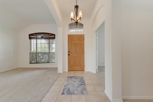 5644 Overland Dr, The Colony, TX 75056 - foyer entrance featuring a chandelier, vaulted ceiling, arched walkways, light carpet, and light tile patterned floors