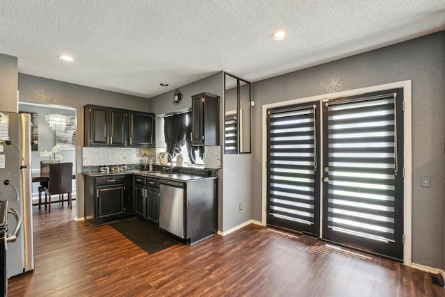 3017 Deanne Ct, Fort Worth, TX 76123 - kitchen with stainless steel appliances, dark wood finished floors, dark countertops, a textured ceiling, and dark cabinets