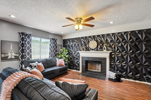 3017 Deanne Ct, Fort Worth, TX 76123 - living room featuring a textured ceiling, wood finished floors, a ceiling fan, a tiled fireplace, and recessed lighting