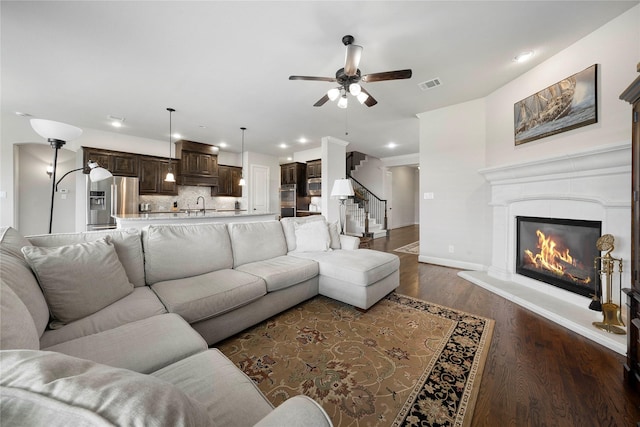8670 Soto Ln, Frisco, TX 75036 - living room with ceiling fan, dark wood-type flooring, stairs, recessed lighting, and a glass covered fireplace