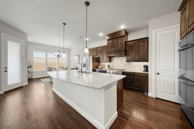 8670 Soto Ln, Frisco, TX 75036 - kitchen featuring appliances with stainless steel finishes, dark wood-style floors, backsplash, a sink, and a kitchen island with sink