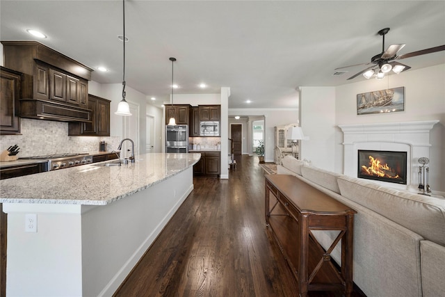 8670 Soto Ln, Frisco, TX 75036 - kitchen featuring open floor plan, appliances with stainless steel finishes, a sink, dark brown cabinets, and dark wood finished floors